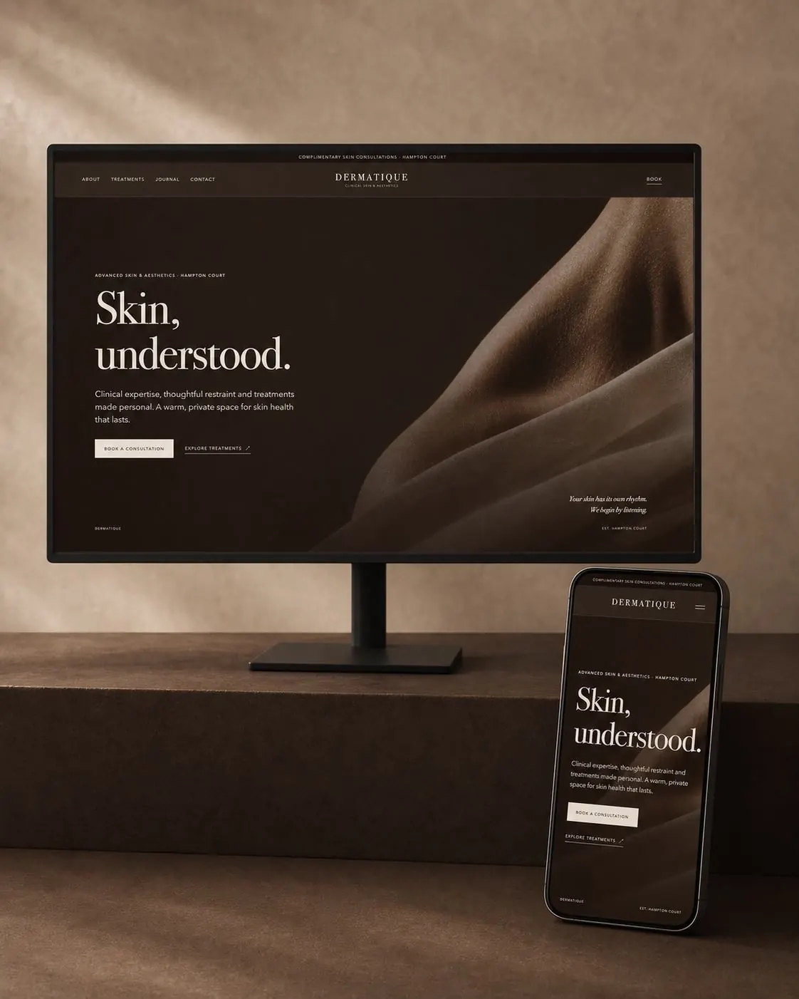 Dermatique website on a desktop monitor and phone in a warm studio setting