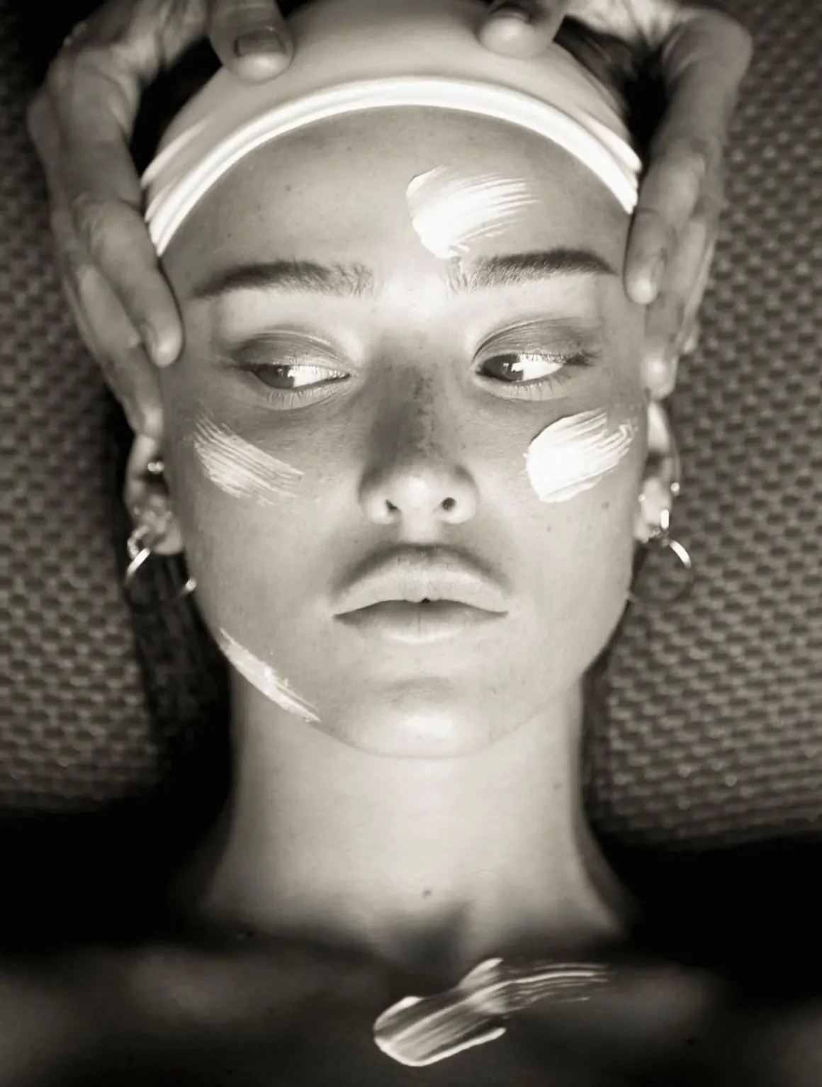 Black and white portrait of a facial treatment, with cream applied across the cheeks