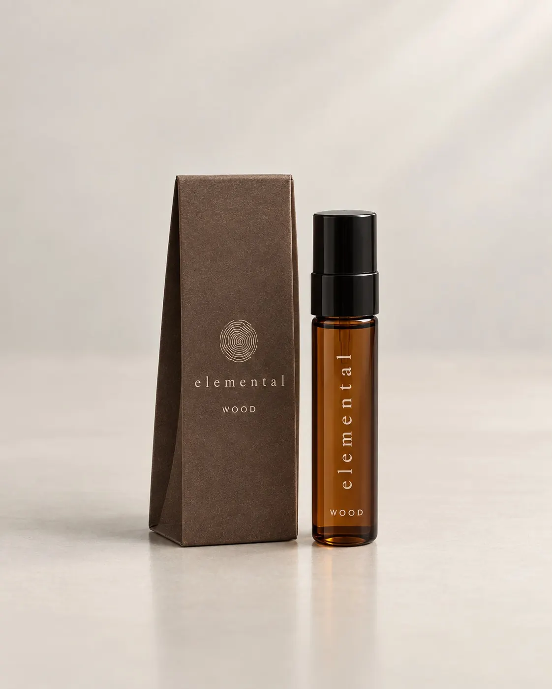 A small Elemental WOOD travel vial beside its kraft sleeve