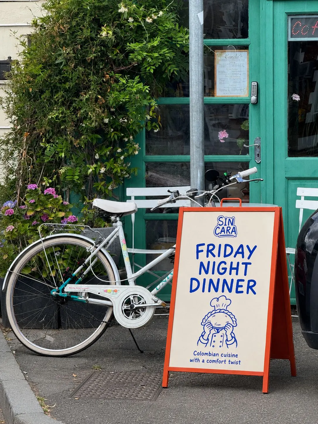 Sin Cara Friday Night Dinner sandwich board outside a café, beside a white bicycle